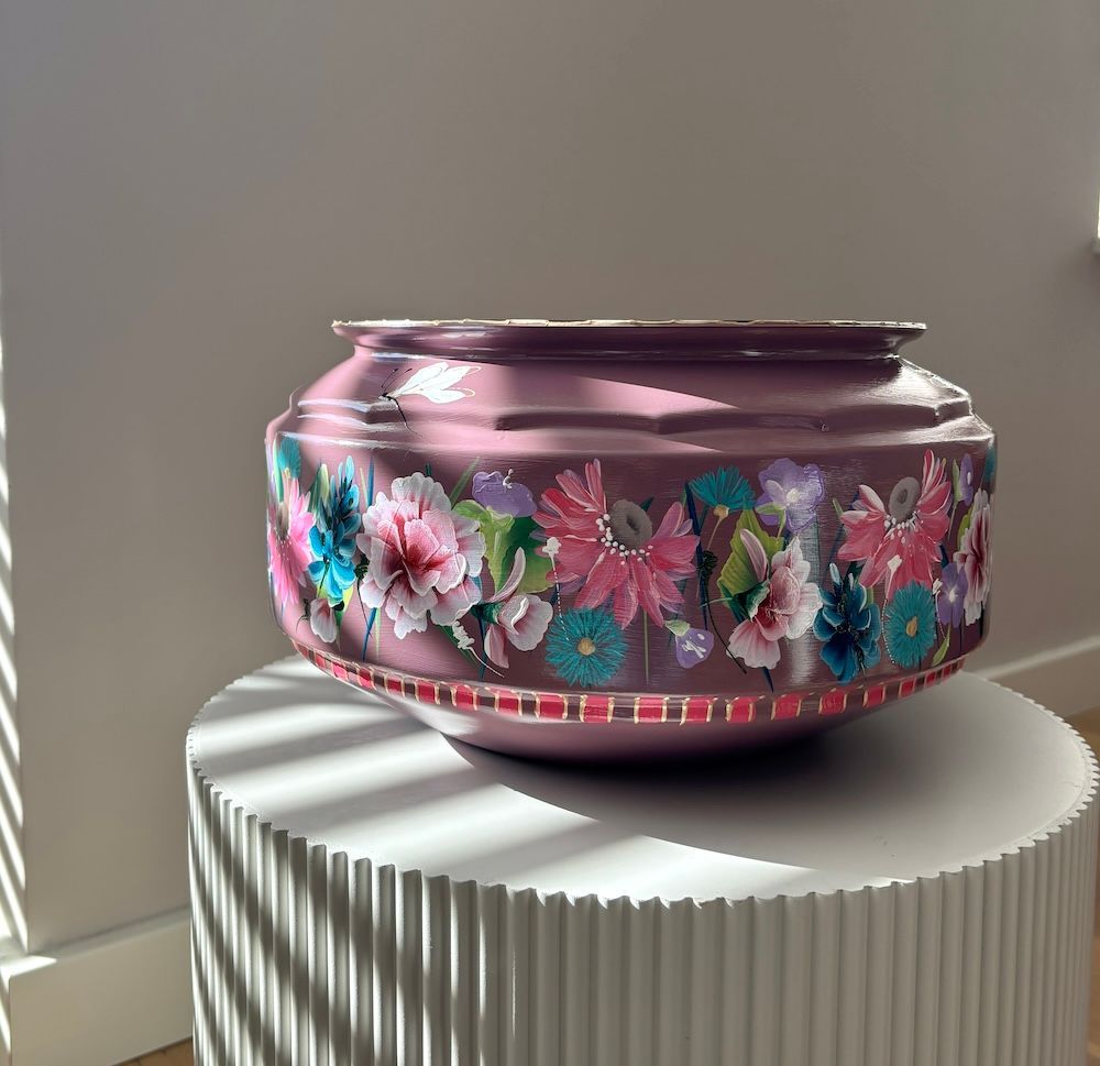 Een pruimkleurige decoratieve schaal met een zwart-wit gestreepte rand, versierd met handgeschilderde bloemmotieven