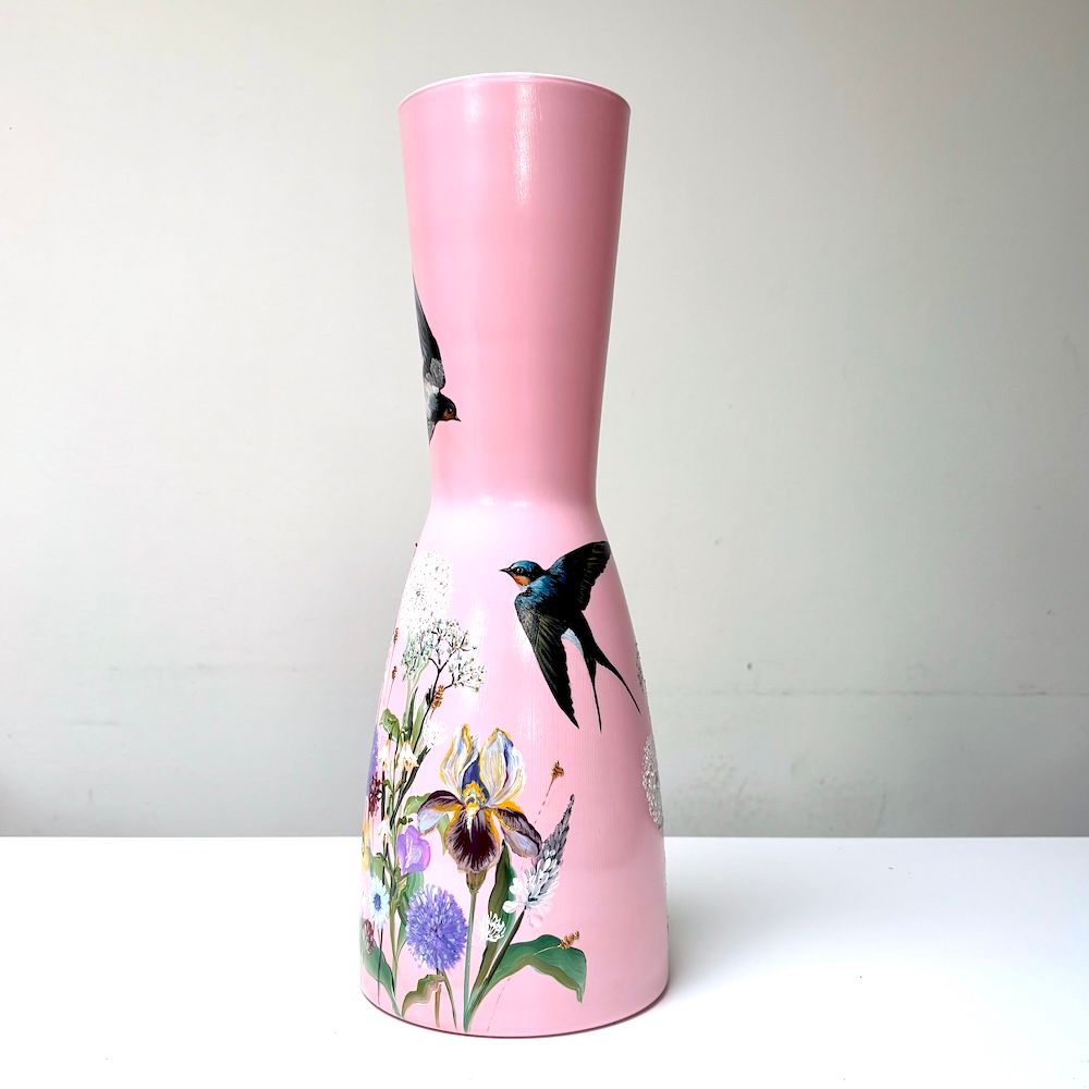 Roze vaas met geschilderde kolibrie en kleurrijke bloemen op een effen achtergrond.