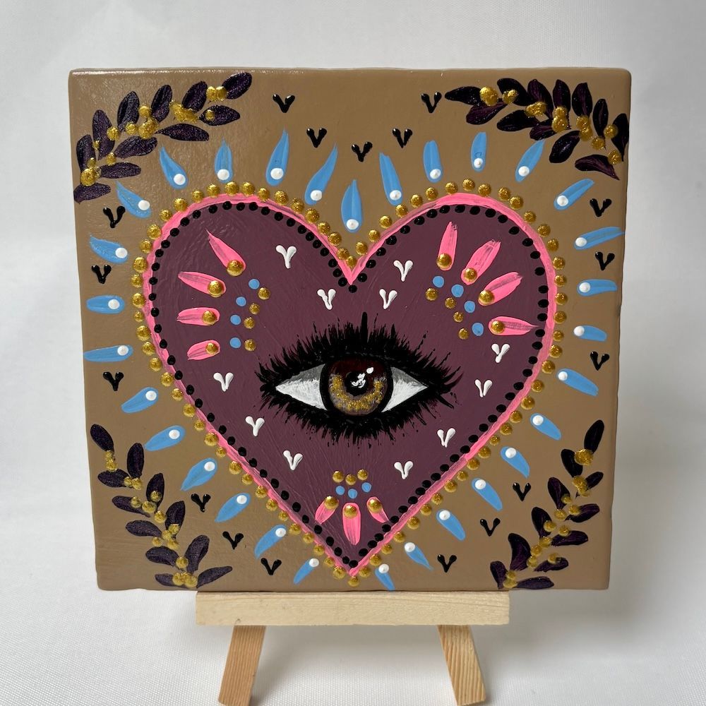 Decoratief canvas met een hartvormig oog in roze en paars, omringd door stippen en bladerrijke takken op een standaard.