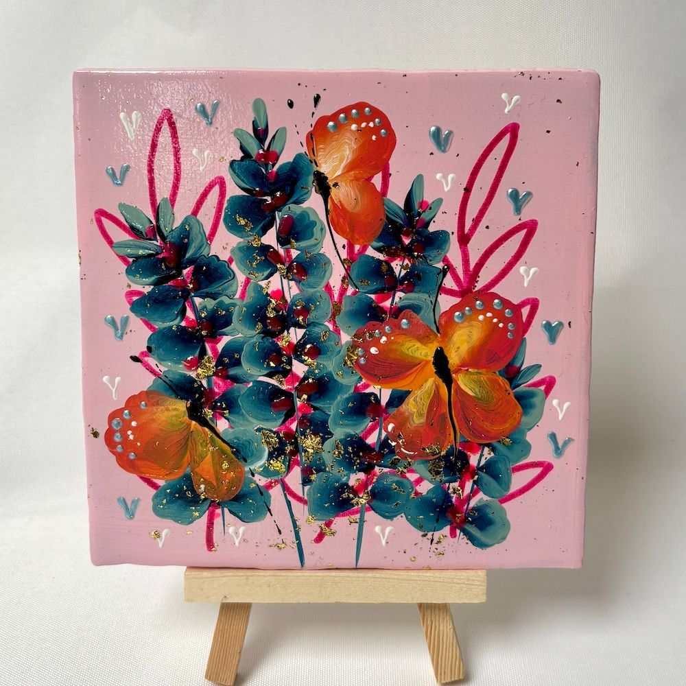Abstracte bloemenschilderij in roze, turquoise, oranje en geel op een kleine schildersezel.