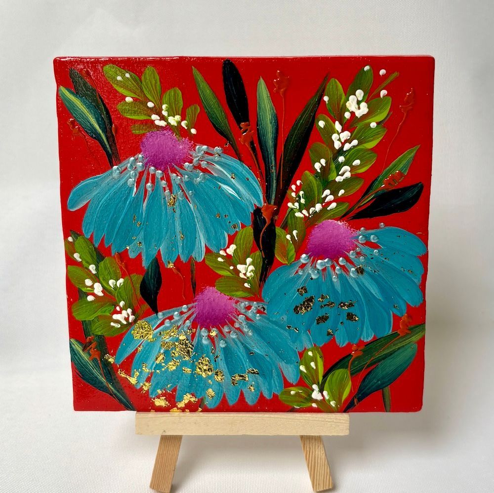 Kleurrijk bloemenschilderij op een schildersezel met blauwe bloemen, groene bladeren en een felrode achtergrond.