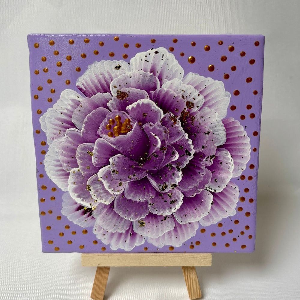 Een paars, goudgespikkeld, gelaagd bloemenschilderij op een klein doek, geplaatst op een miniatuur houten schildersezel.