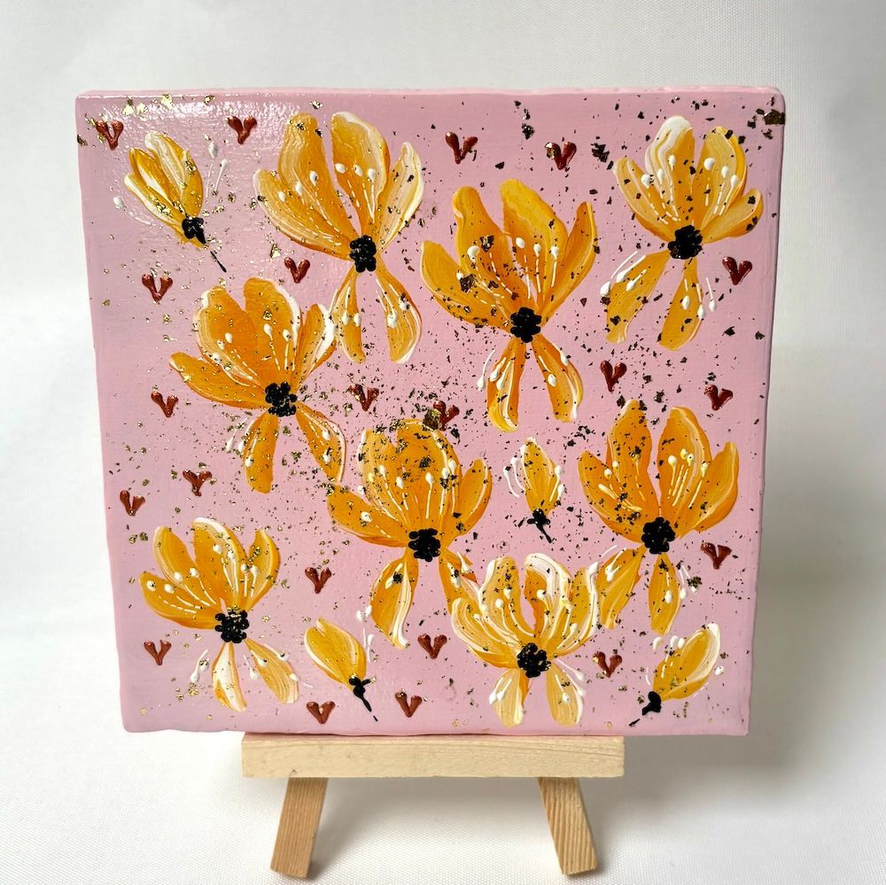 Roze canvas met gele bloemen en kleine vlinders op een klein houten schildersezel.