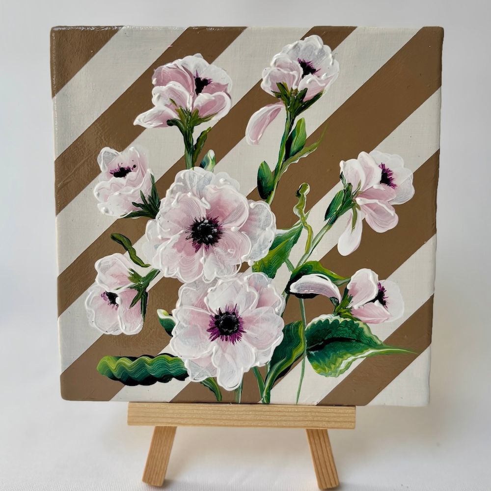 Acrylverf op een tegel van lichtroze bloemen met donkere centra op een beige en crèmekleurige gestreepte achtergrond