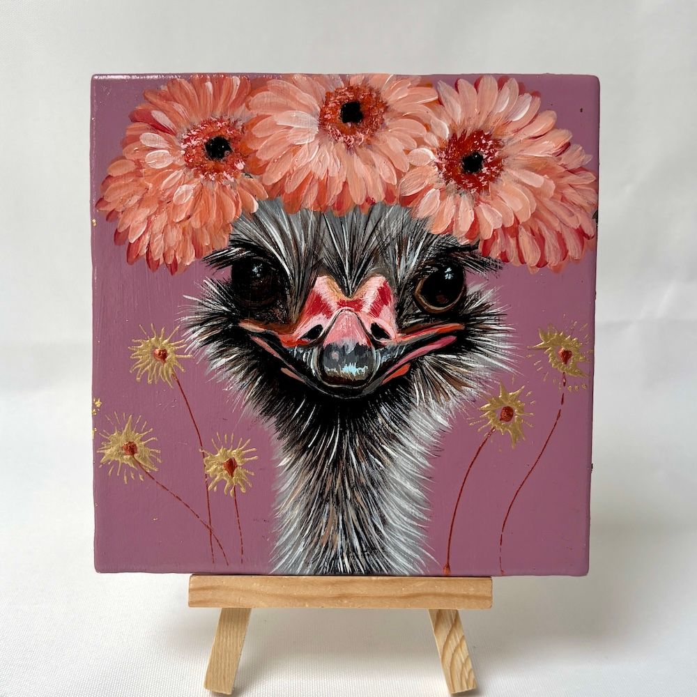 Een vierkant tegeltje waarop een struisvogel met een kroon van roze bloemen te zien is tegen een stoffige paarse achtergrond.