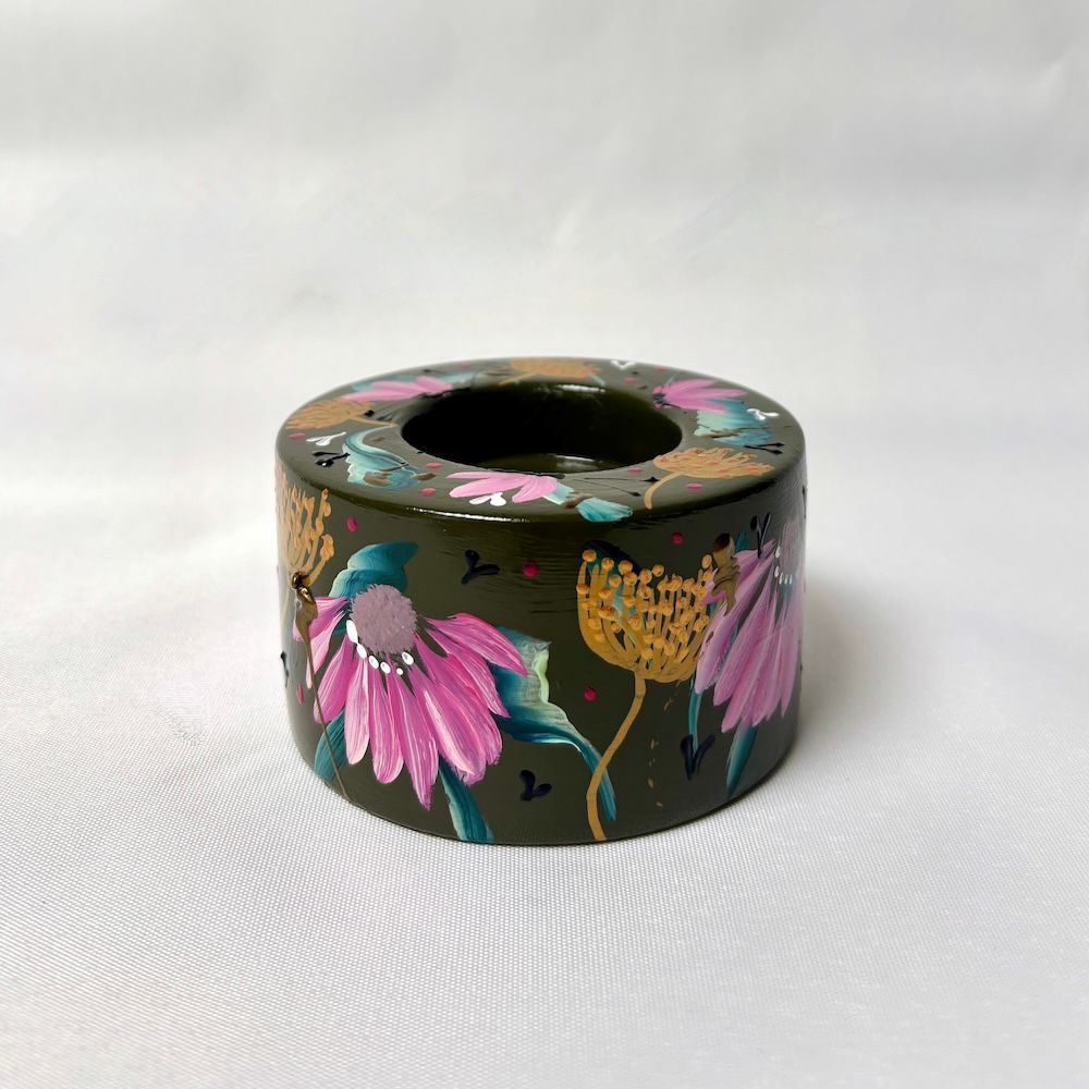 Een donkergroene  kaarsenhouder, handbeschilderd met roze echinaceabloemen en abstracte botanische motieven in goudkleur.
