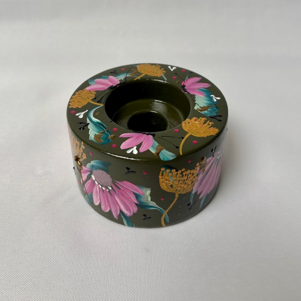 Een donkergroene  kaarsenhouder, handbeschilderd met roze echinaceabloemen en abstracte botanische motieven in goudkleur.