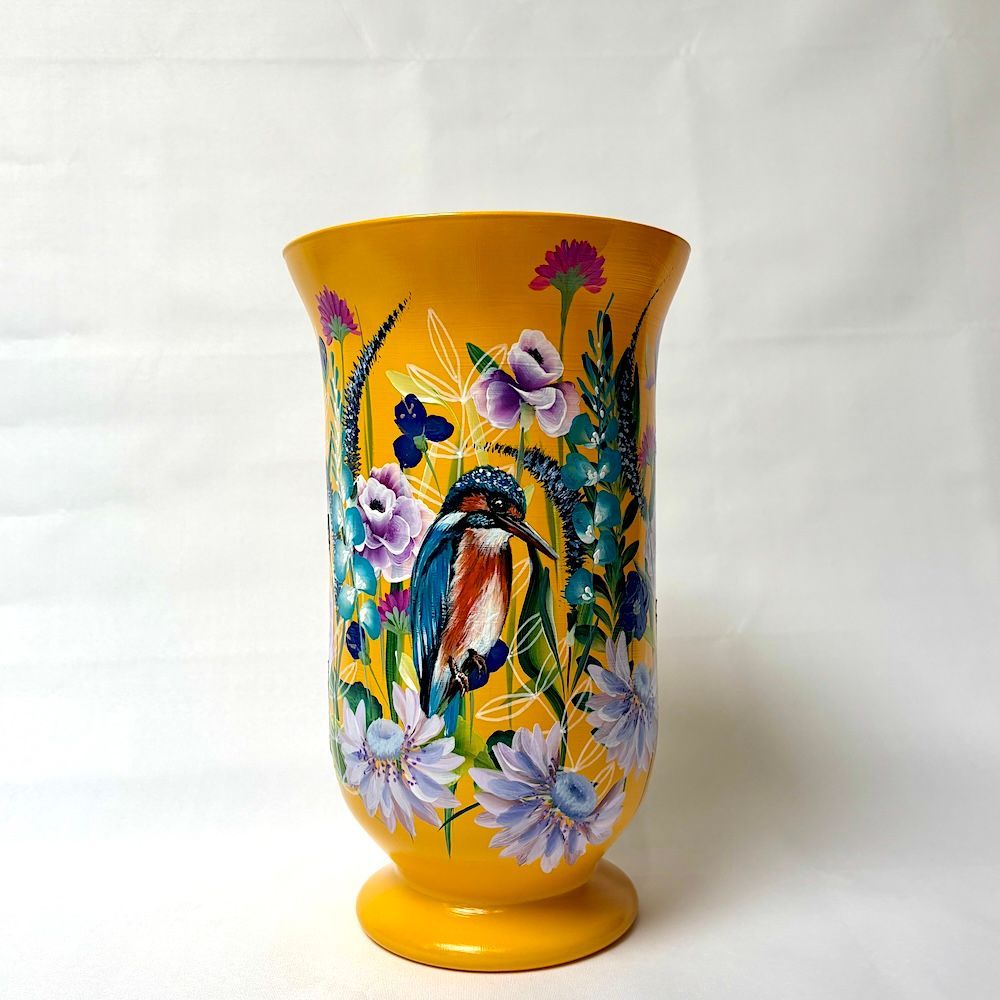 Een felgele decoratieve vaas, handbeschilderd met een ijsvogel in het midden, omringd door diverse kleurrijke bloemen.