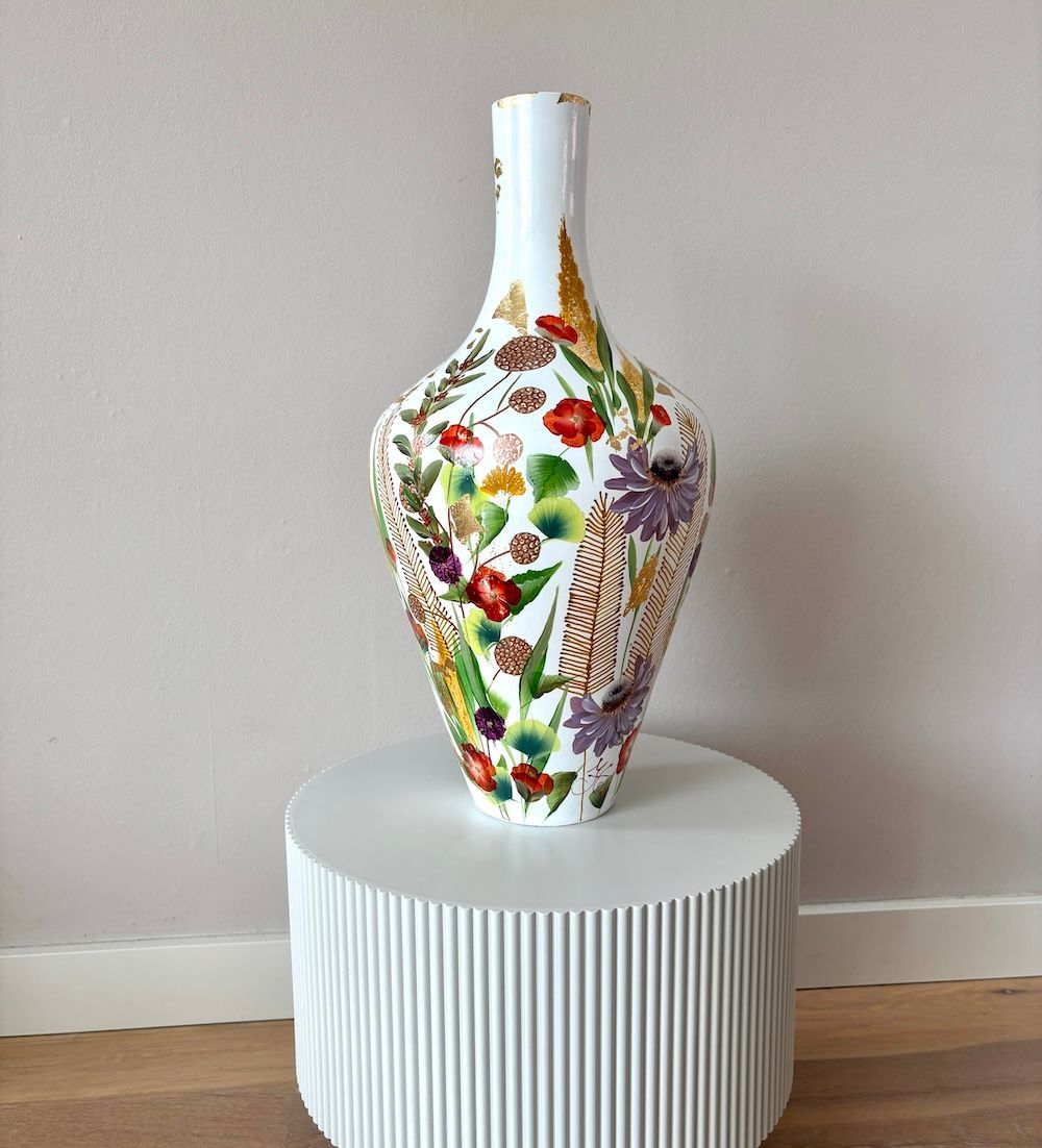 Decoratieve witte vaas met kleurrijke accenten en een zwart zwaanmotief op een gestreepte bijzettafel.