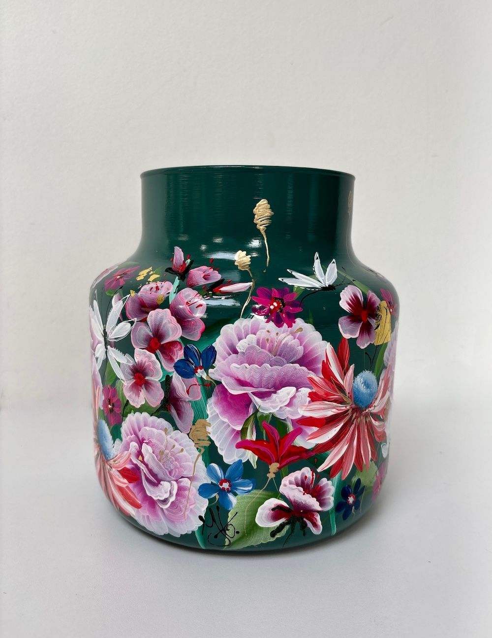 Een donkergroene vaas beschilderd met een levendig, kleurrijk bloemenpatroon van roze, witte en rode bloemen