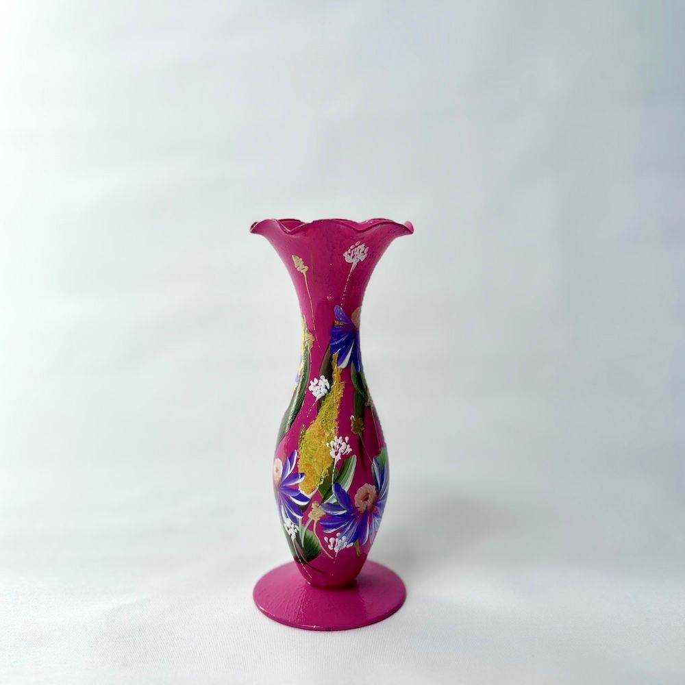 Een magenta vaas met een gegolfde bovenkant, versierd met handgeschilderde blauwe en gouden bloemmotieven