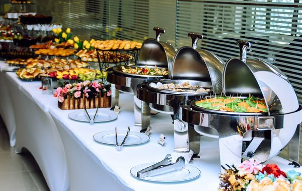 Buffet table with various foods, including chafing dishes, appetizers, and decorations.