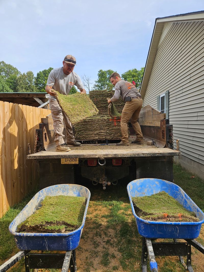 Two men unloading sod from a truck.
