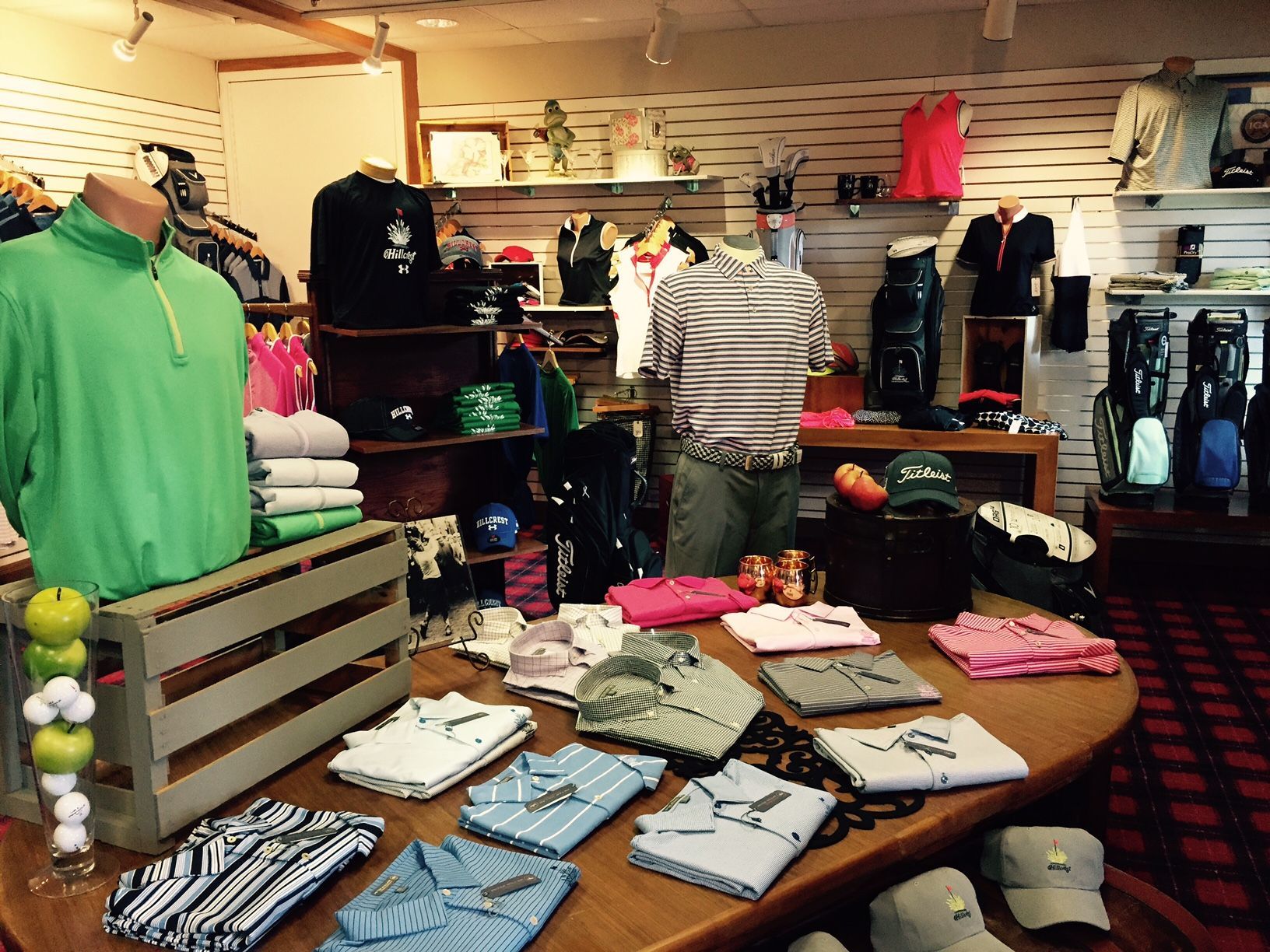 Golf apparel and accessories displayed in a shop, including shirts, bags, and hats.