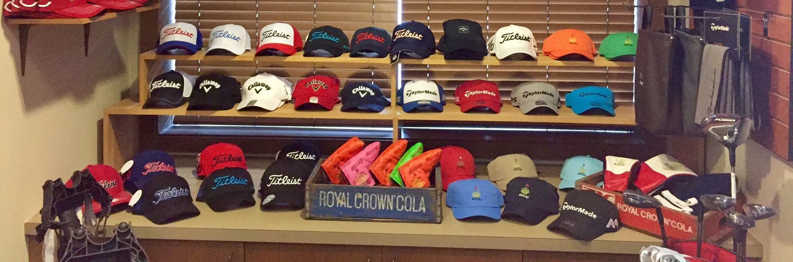 A display of golf hats of various colors and brands on shelves near a window.