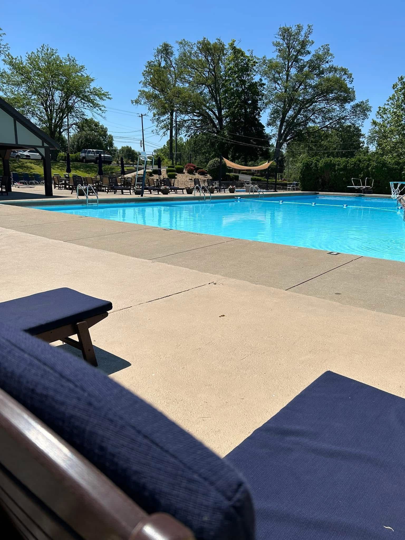 Lounge chair with blue cushions by a blue pool on a sunny day.