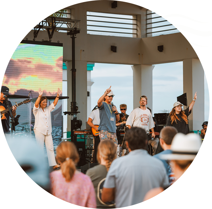 Outdoor concert stage with performers singing and gesturing to a crowd