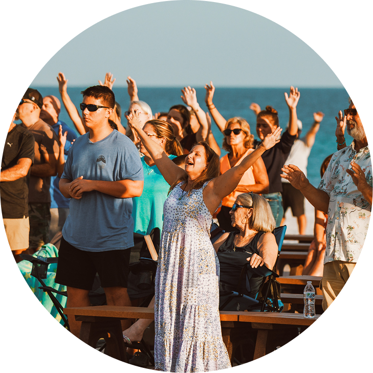 People dancing and raising hands at an outdoor beach gathering
