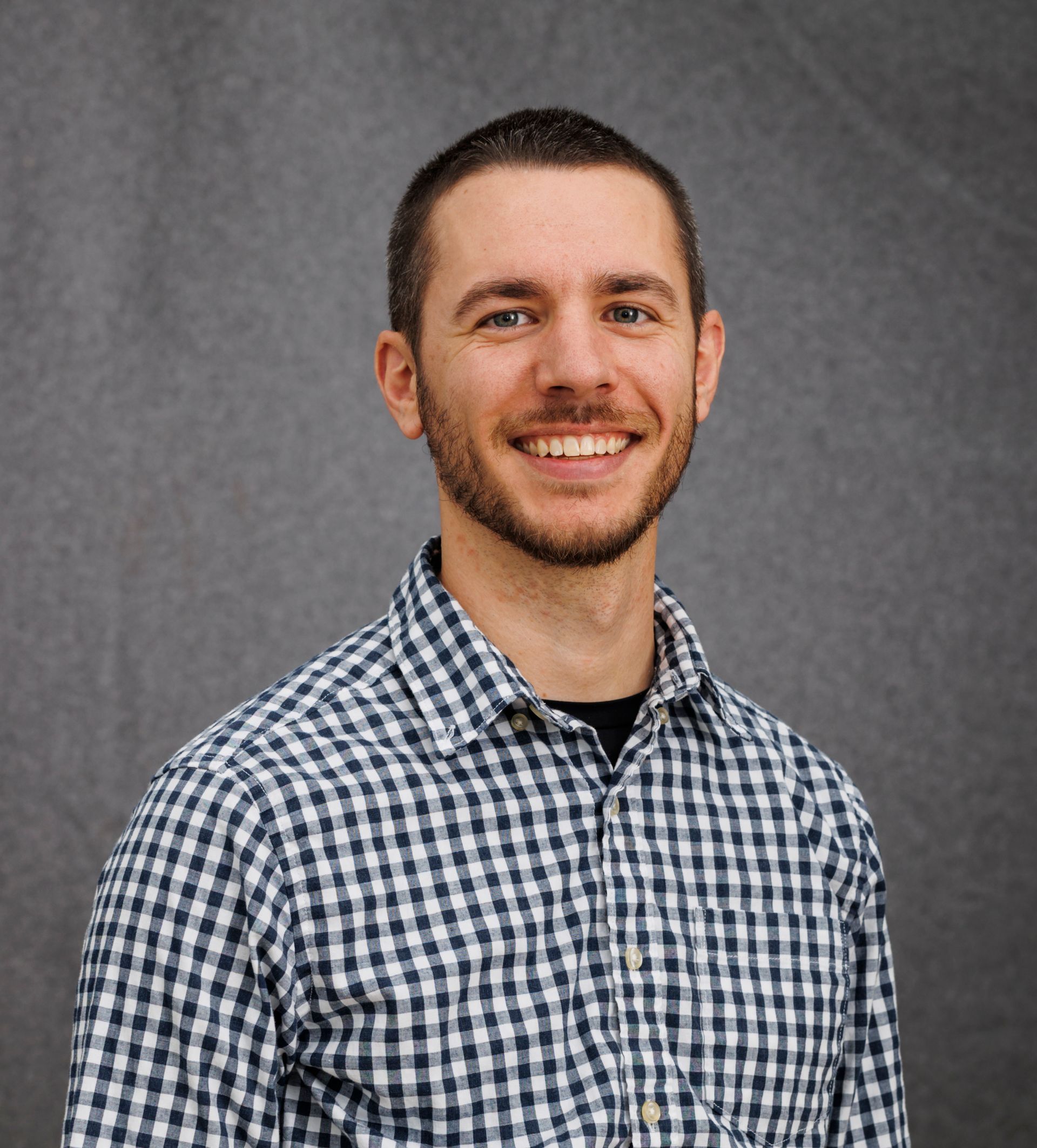 A man in a plaid shirt is smiling for the camera.