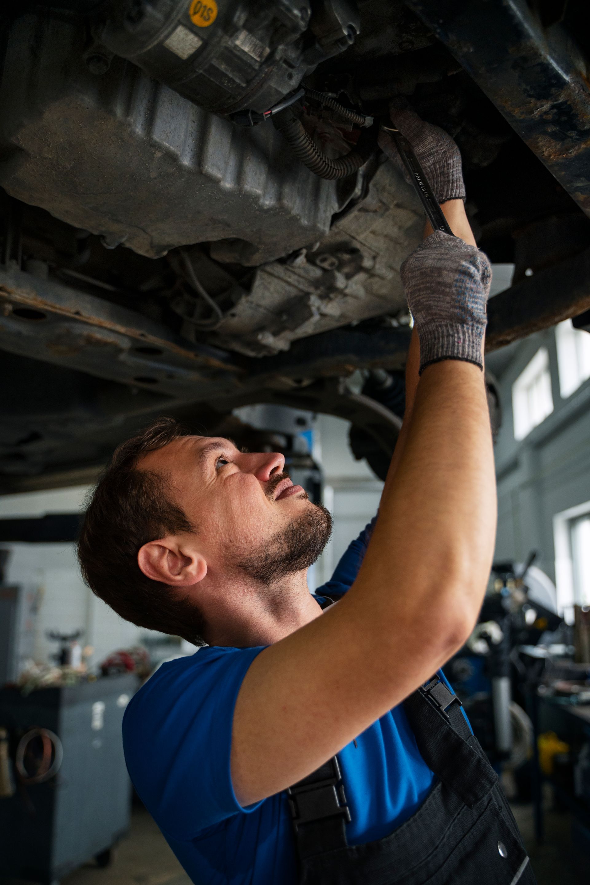 A man is working under a car in a garage.