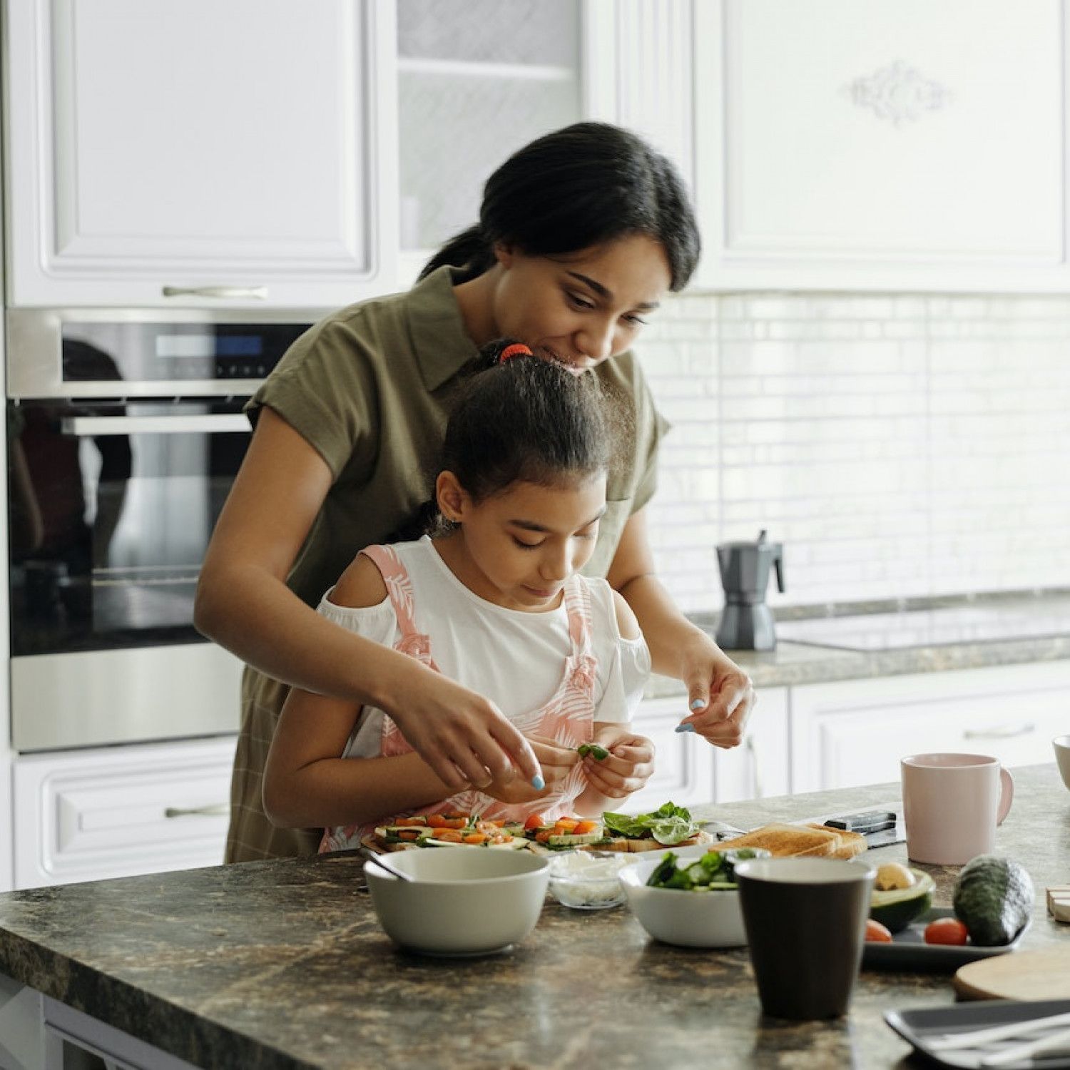 Two people preparing food together in a bright kitchen, mixing ingredients at a counter