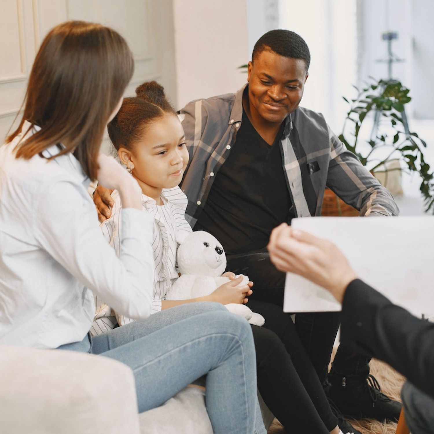 Three people in a counseling session, seated in a bright room and talking with a therapist.