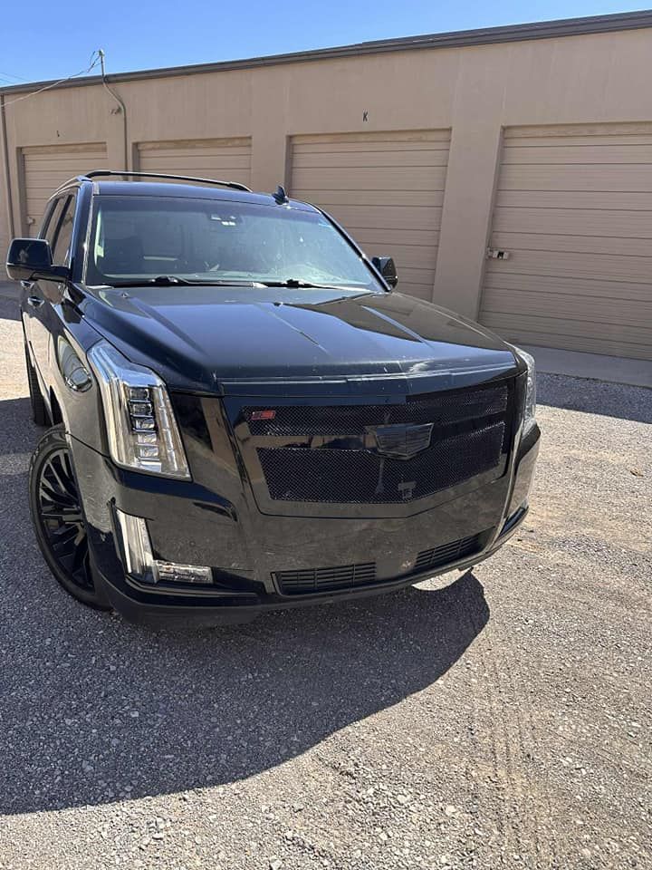 Black SUV parked in front of beige garage doors in a sunlit lot