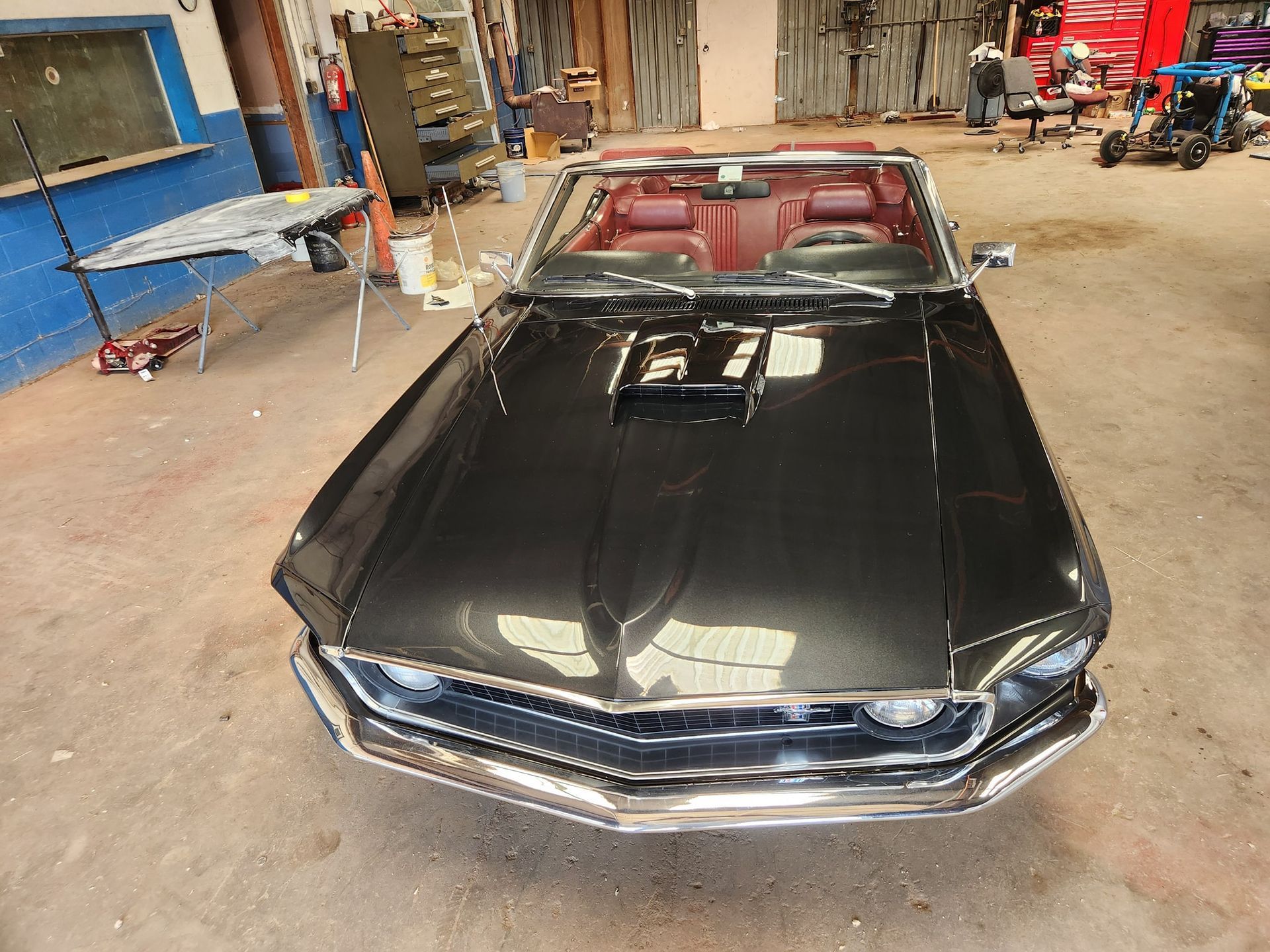 Black classic muscle car with hood scoop parked in a workshop garage