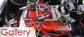Red racing engine with chrome carburetors and red hoses in a garage display, labeled “Gallery” Red racing engine with chrome carburetors and red hoses in a garage display, labeled “Gallery”