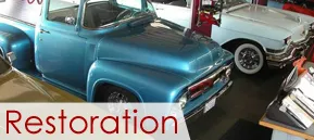 Classic blue pickup and white car in a garage with “Restoration” text Classic blue pickup and white car in a garage with “Restoration” text