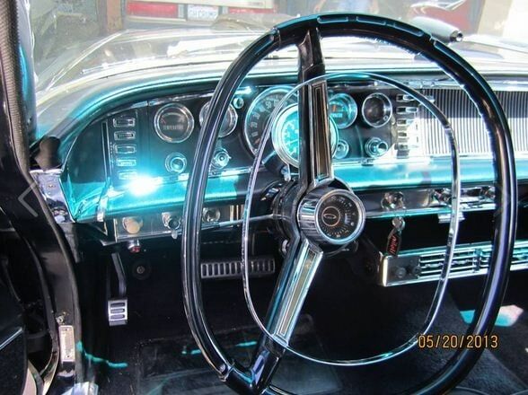 Vintage car dashboard and steering wheel with bright blue interior lighting