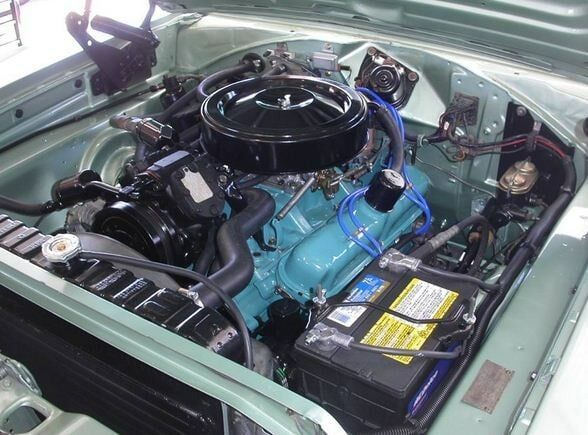 Classic car engine bay with turquoise engine and black air cleaner under the hood
