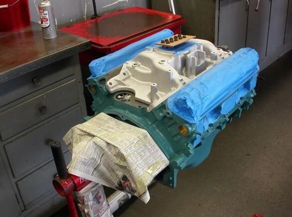 Blue engine block on a workbench in a garage, with a towel draped over one end and tools nearby