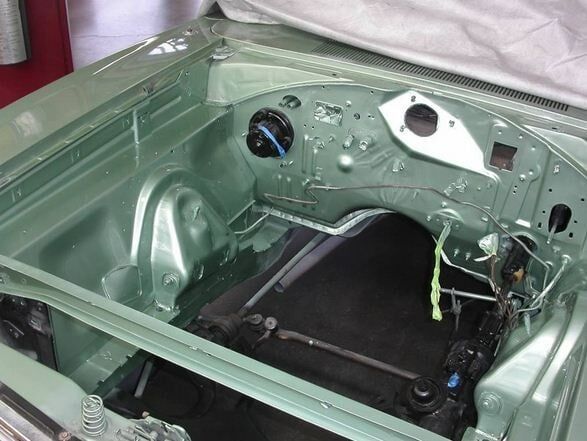 Green car interior shell with dashboard and floor removed, showing an empty body frame