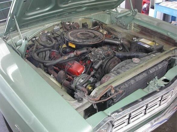 Open car hood showing an engine bay with a round air cleaner and red engine parts