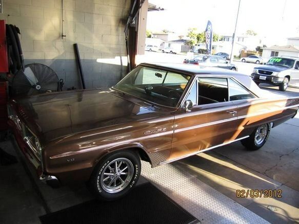 Brown classic muscle car parked indoors under bright light, shown in side view