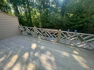 Wooden deck with decorative railing, trees in the background.