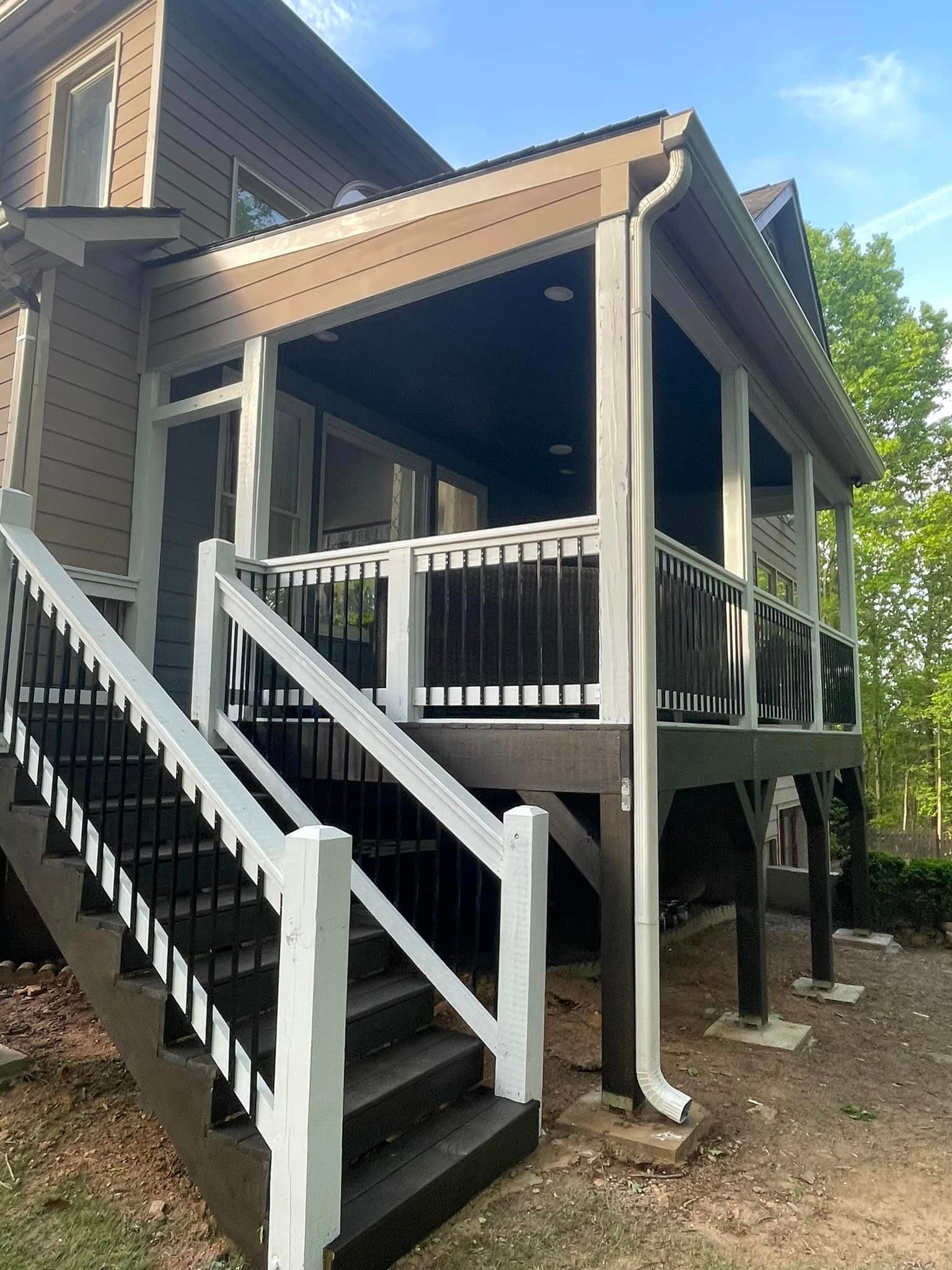 Exterior view of a house with a screened porch and stairs painted black and white; brown siding, gray gutters.