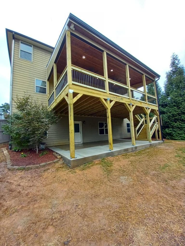 Two-story house with a wooden deck and covered porch. Ground level has a concrete patio.