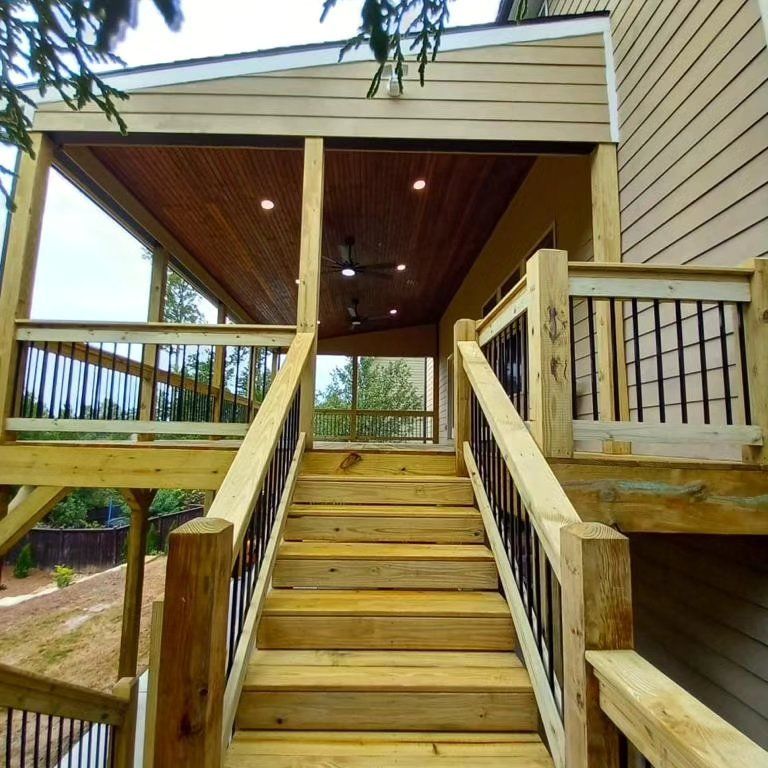Wooden deck with stairs leading to a covered area, black railings.
