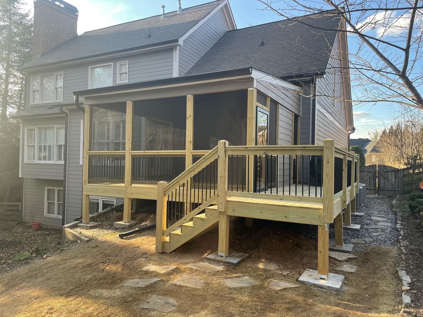 Backyard deck with screened porch, wooden structure with steps, gray house.