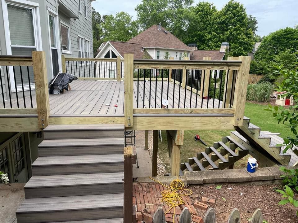 Multi-level wooden deck with steps, overlooking a yard and houses.