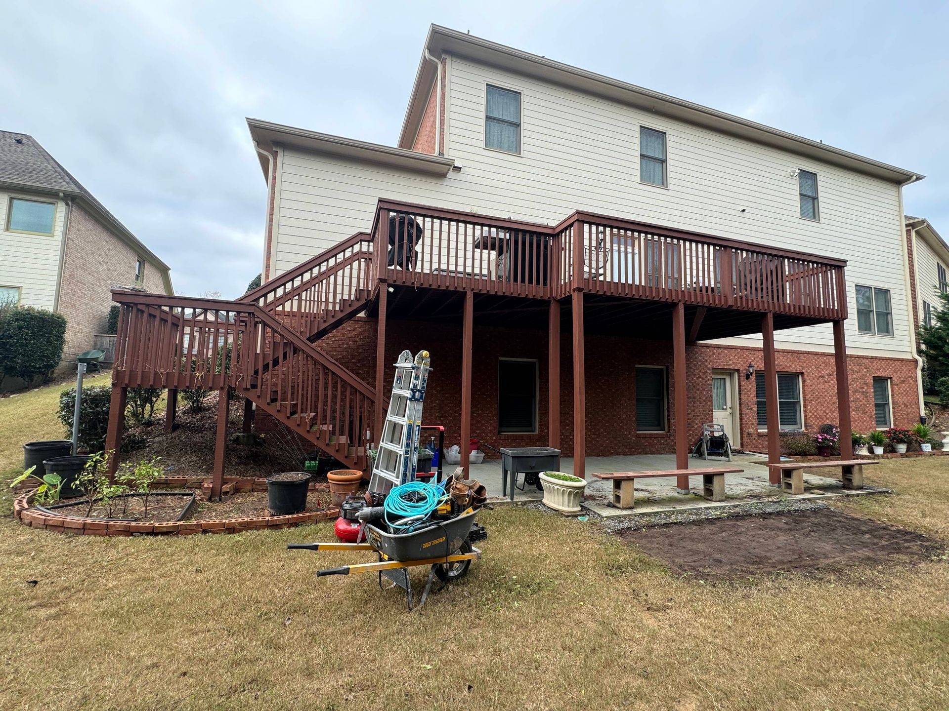 Backyard view of a two-story house with a large wooden deck painted dark brown and lawn.