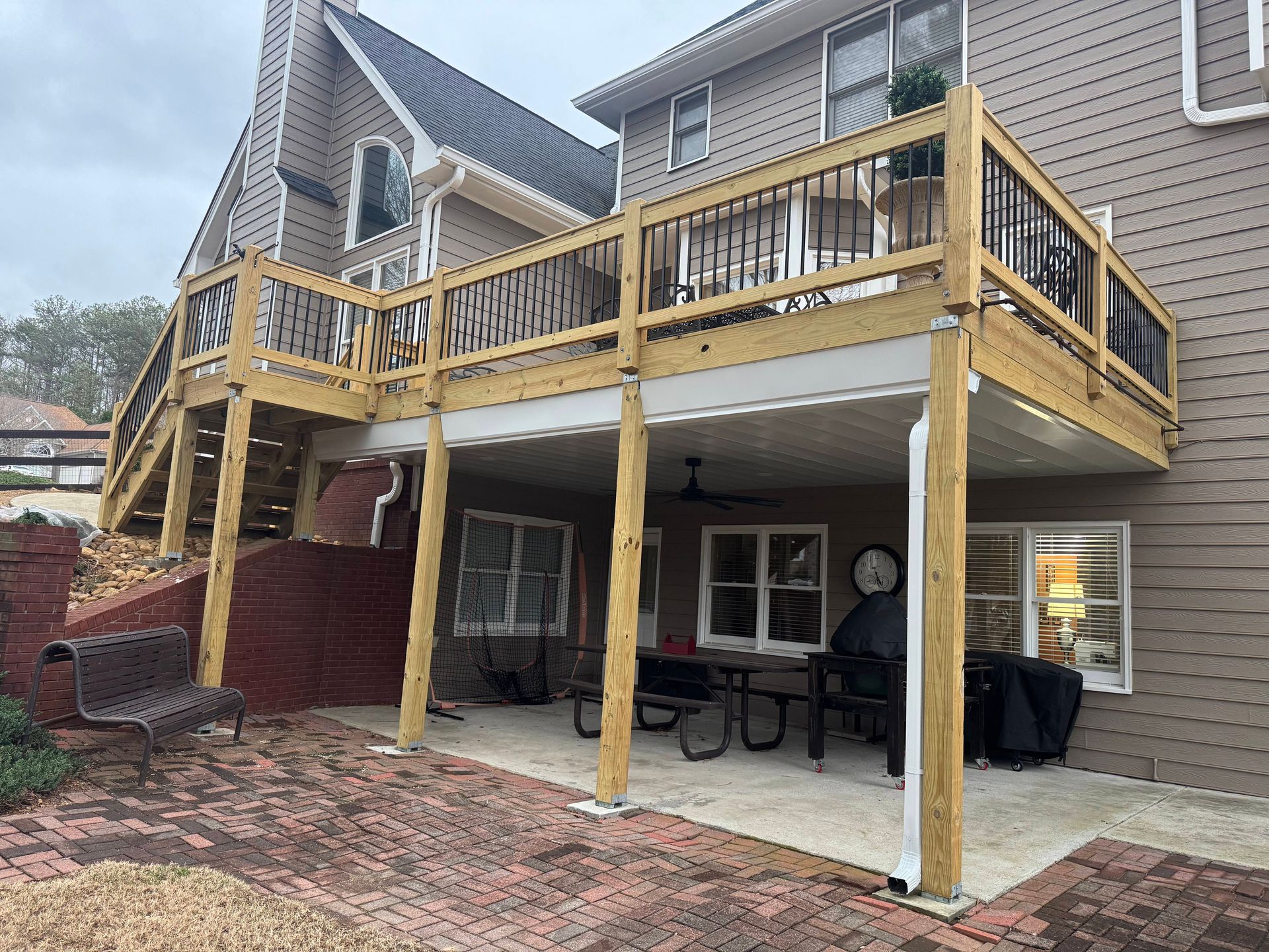 Wooden deck over patio on a house with brick and siding.