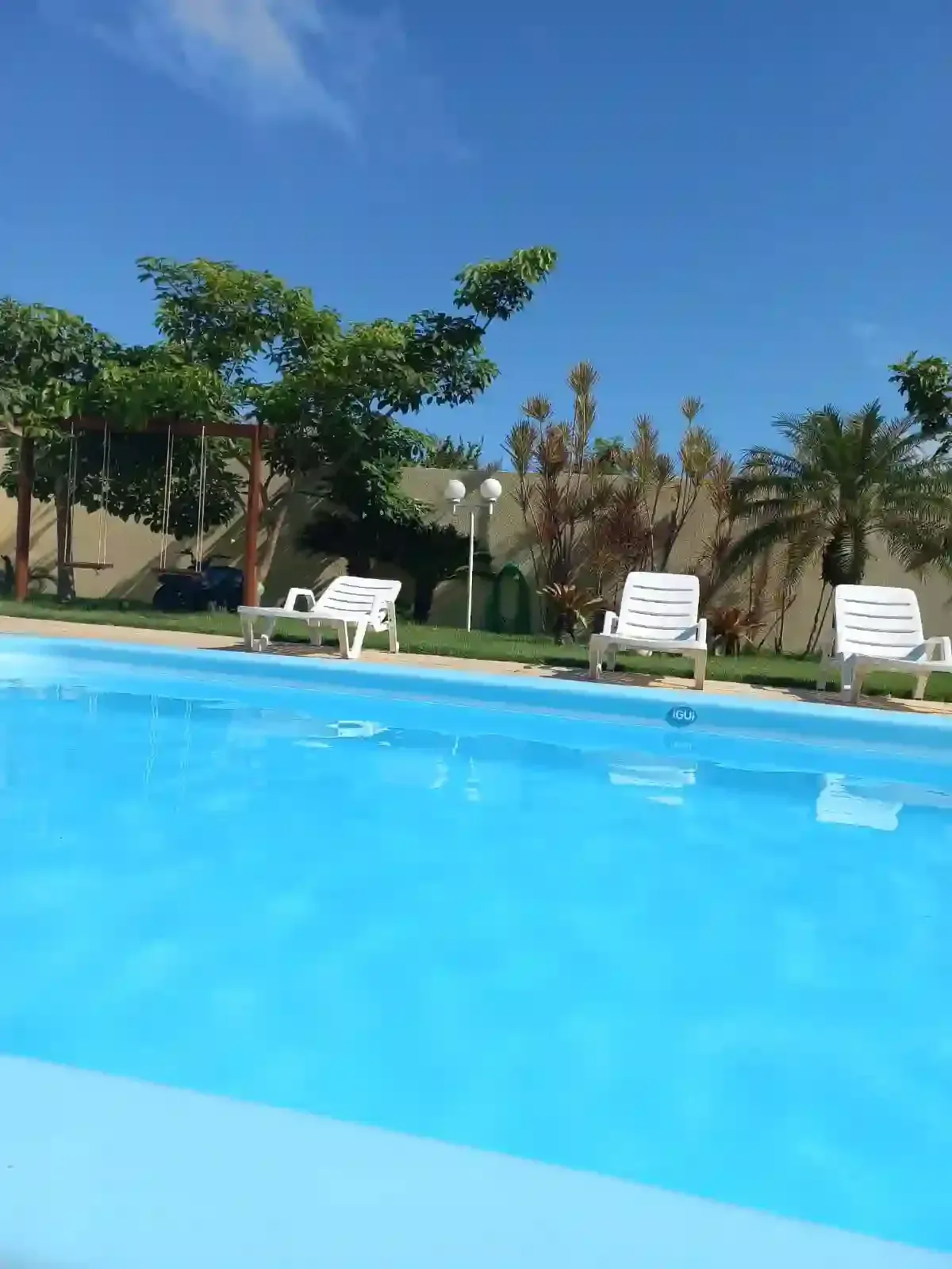 Um homem está sentado na beira de uma piscina em frente a um hotel.