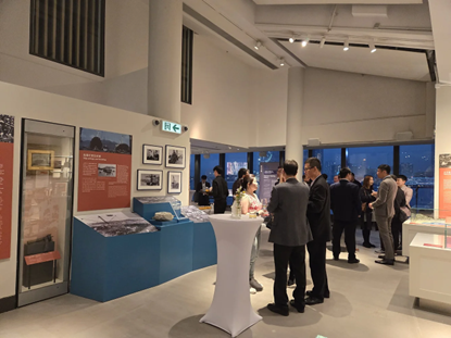 人們在現代博物館展廳參加活動，展廳內有展覽品，還能欣賞海港景色。