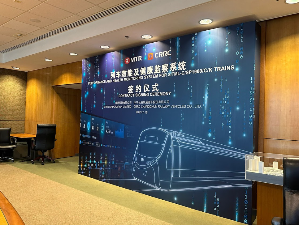 儀式背景：列車示意圖、藍色背景、中文文字以及港鐵和中車的標誌。