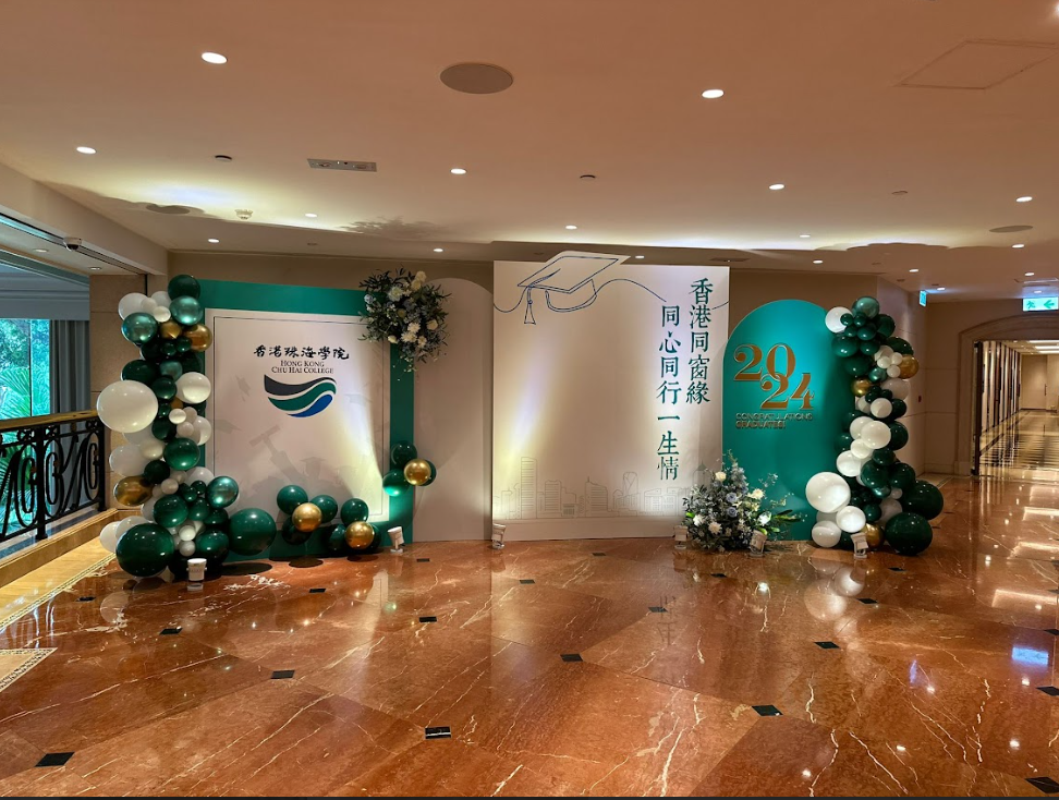 活動背景是綠色和金色的氣球拱門，以及兩塊寫有中文的白色面板，擺放在一個閃亮的大廳裡。