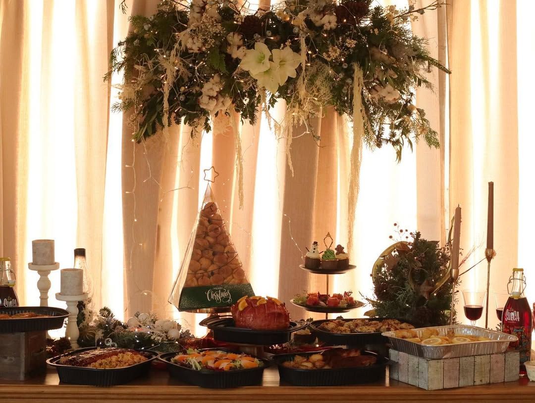 Holiday feast featuring a roasted turkey, leg of lamb, cakes, pastries, and festive decorations.