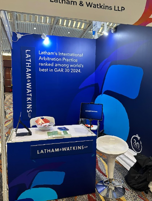 Latham & Watkins LLP 的展位位於會議中心內，配有桌子、椅子和宣傳品。